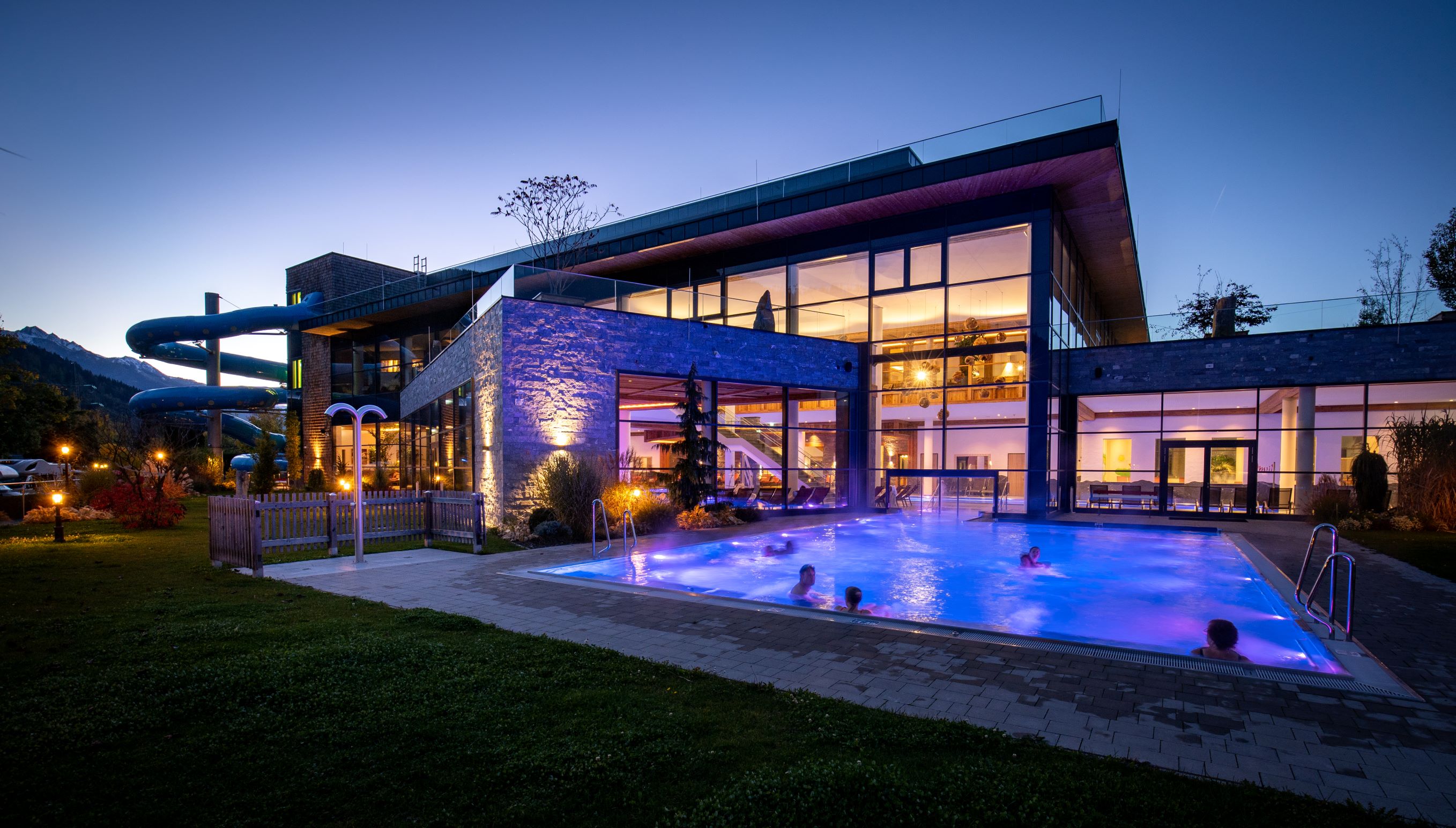 Nachtansicht des Sportcamps Woferlgut mit beleuchtetem Außenpool und Wasserrutsche.