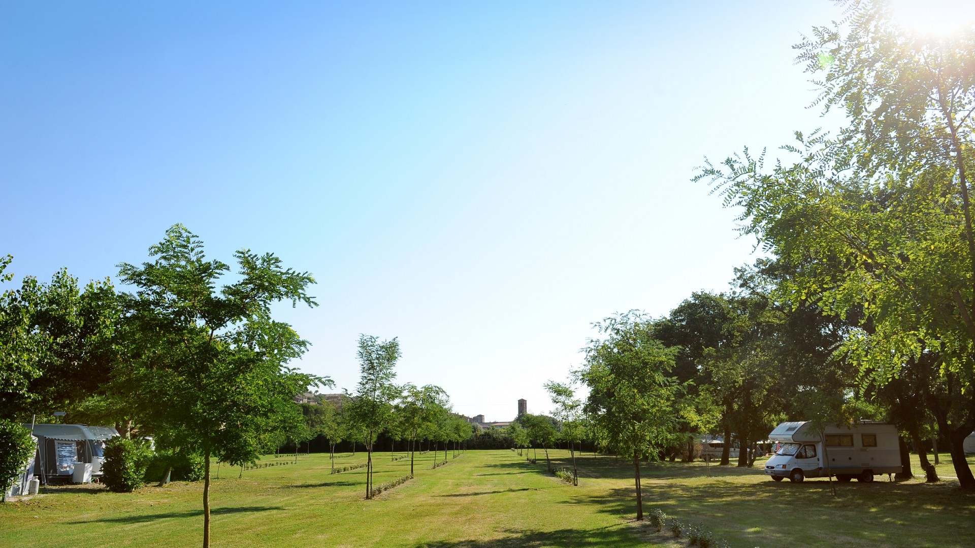 Campsite with a camper under trees, Parco delle Piscine.
