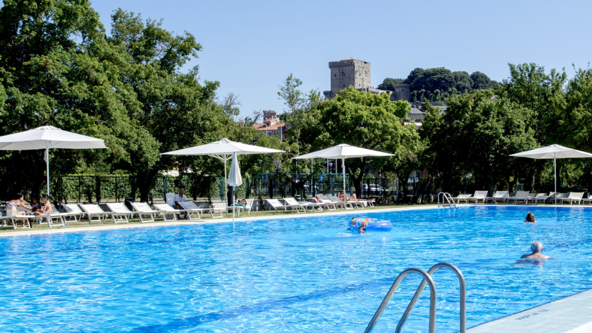 Campsite with a swimming pool under umbrellas.